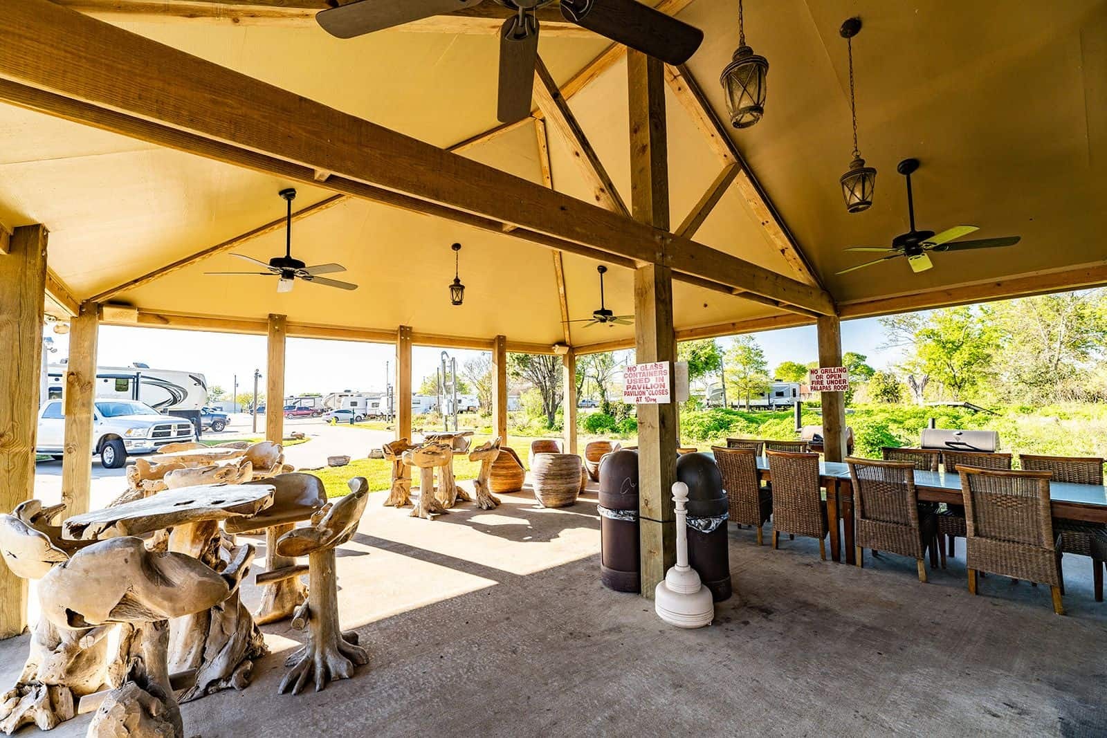 Covered BBQ pavilion with rustic wood furniture and ceiling fans