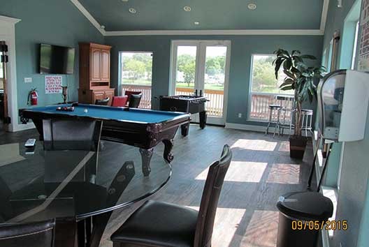 Clubhouse game room with pool table, foosball, flat-screen TV, and bar seating