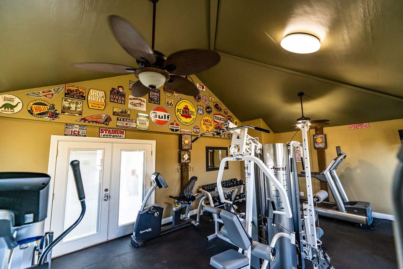Fitness center with vintage signage, cardio machines, and weight equipment — Gulf Coast 5 Star RV Resort